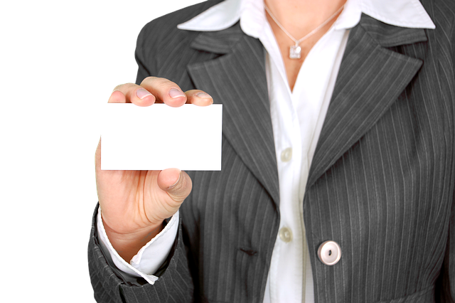 female in a business suit without her head shown with a business card in her hand